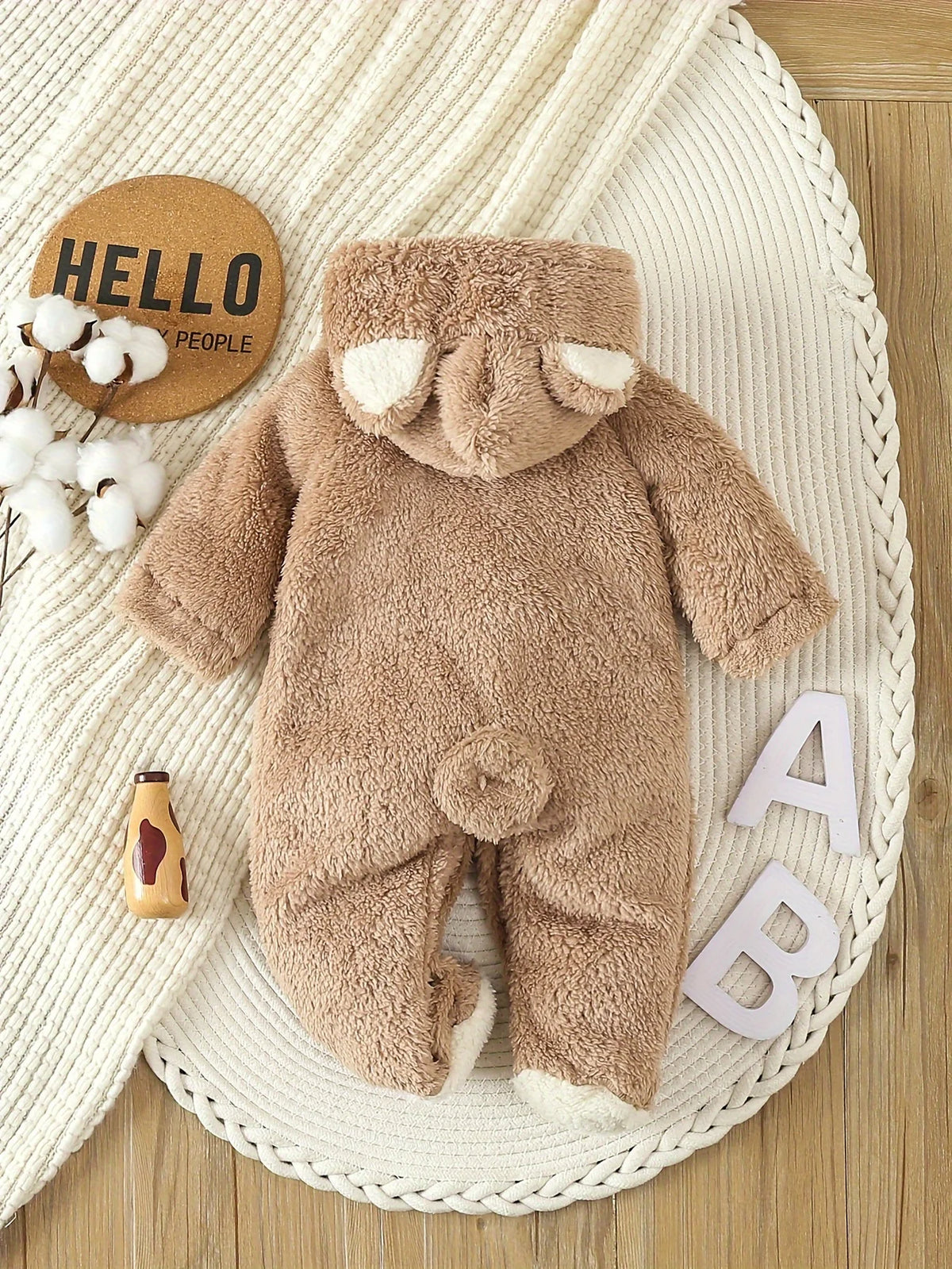 Baby sitting in a brown hooded bear romper