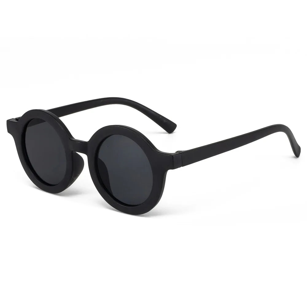 Child smiling in round sunglasses at the beach