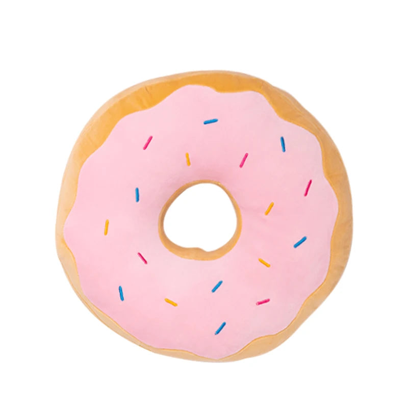 Giant donut plush pillow on a bed with cushions
